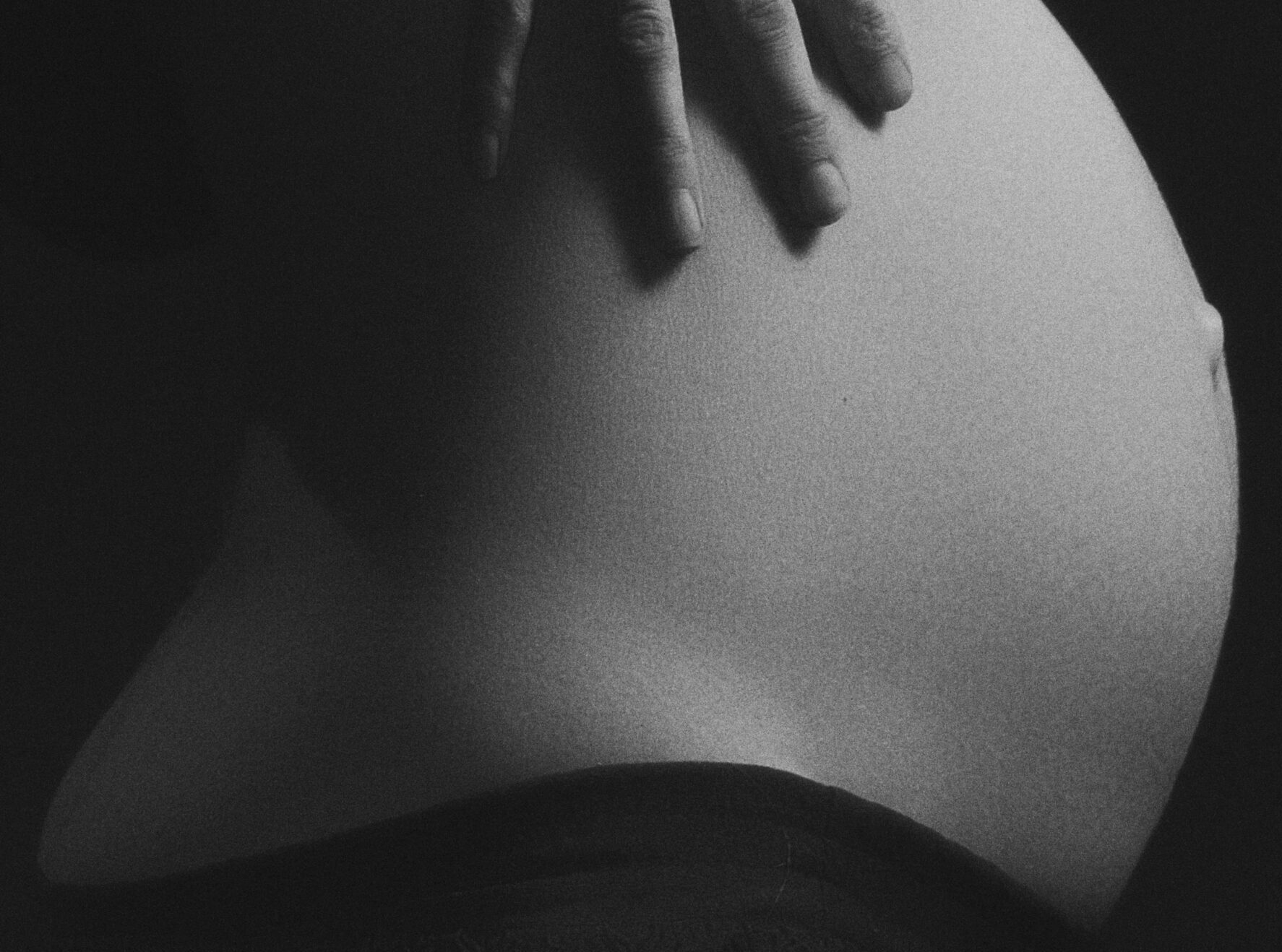 Grayscale Photo of Pregnant Woman Holding Stomach